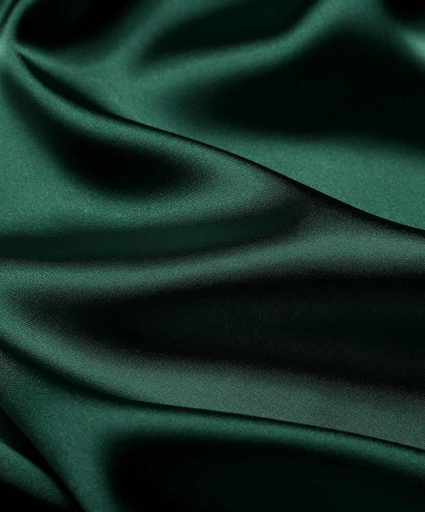 Close-up of dark green satin fabric with smooth, glossy drape