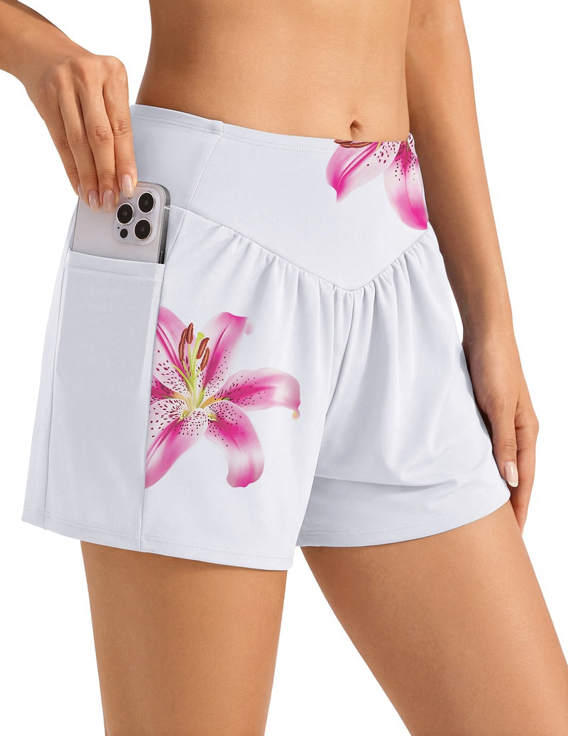 High-waist swim shorts, white with pink lily print, elastic waist and side pockets.