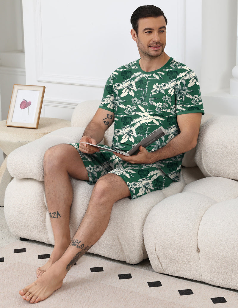 Men's leaf-print pajama set, green top and shorts, seated side view.