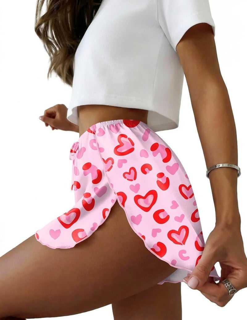 Pink heart-print satin pajama shorts with side slit, elastic waistband and drawstring.