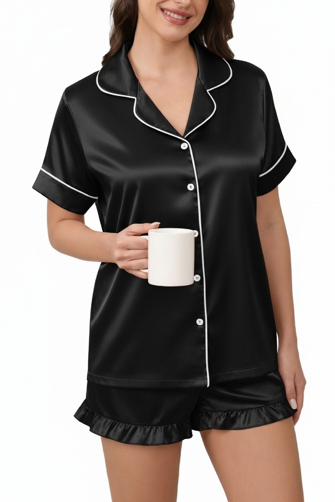 Black satin pajama set with collared button-up top and ruffle-trim shorts holding a mug