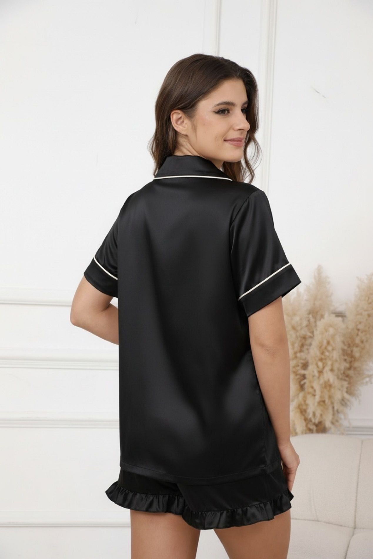 Black satin short-sleeve pajama top with collared button placket and ruffle hem shorts