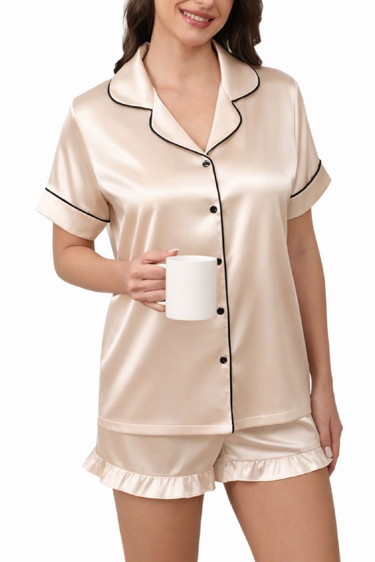 Cream satin pajama set with short-sleeve collared button-up top and ruffle hem shorts holding a mug