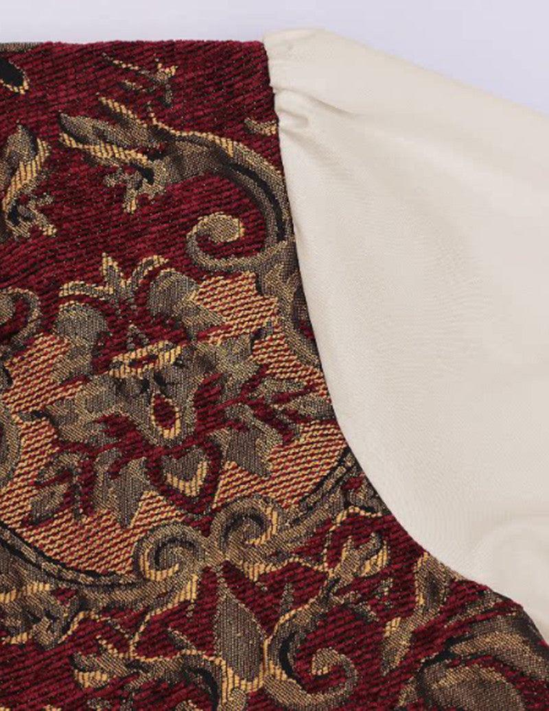 Burgundy and gold jacquard fabric close-up with ornate scroll pattern and trim
