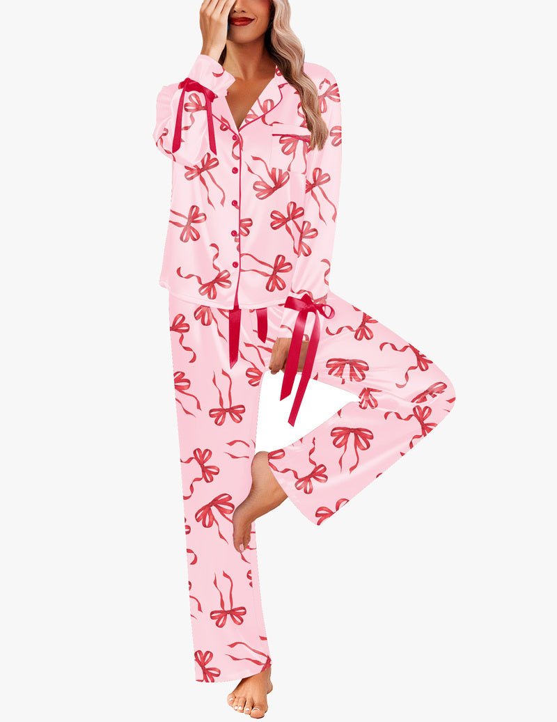 Pink satin pajama set with red bow print, button-down top and long pants