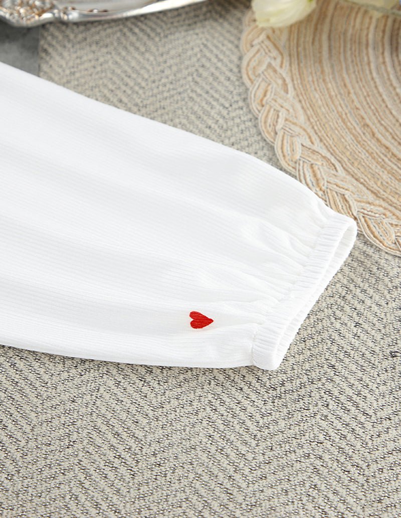 White wide-leg lounge pants cuff with red heart print and elastic gather.