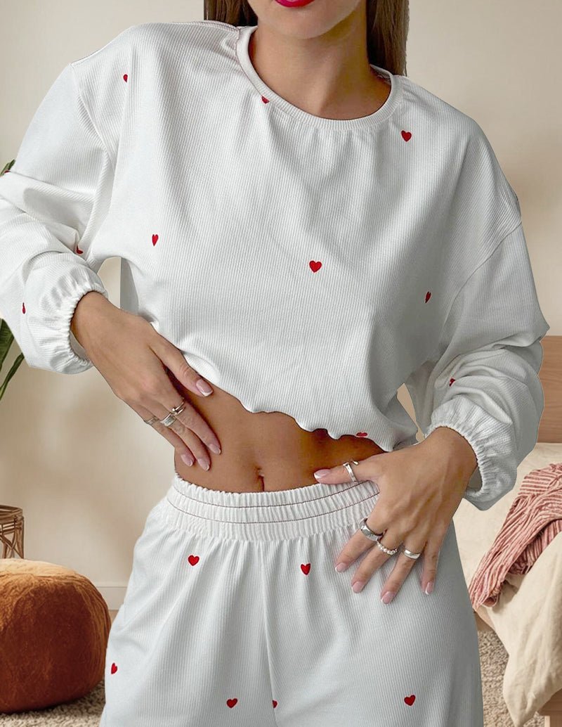 White cropped long-sleeve lounge top and matching wide-leg pants with red heart print.