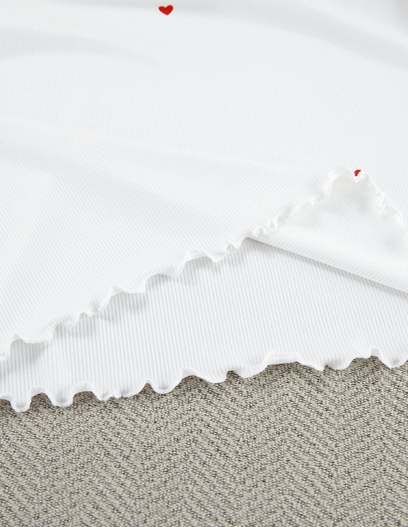 White ruffled top hem with small red hearts and scalloped edge trim.