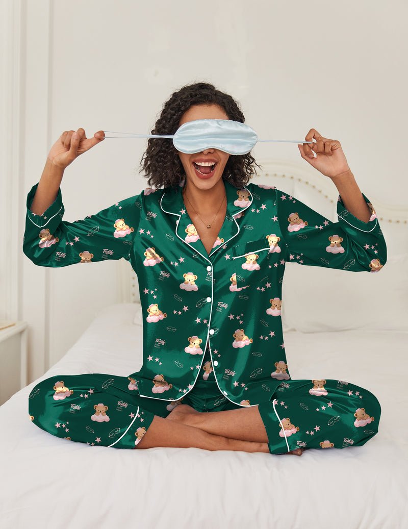 Green satin pajama set with button-front shirt and allover cartoon print; wearing sleep mask