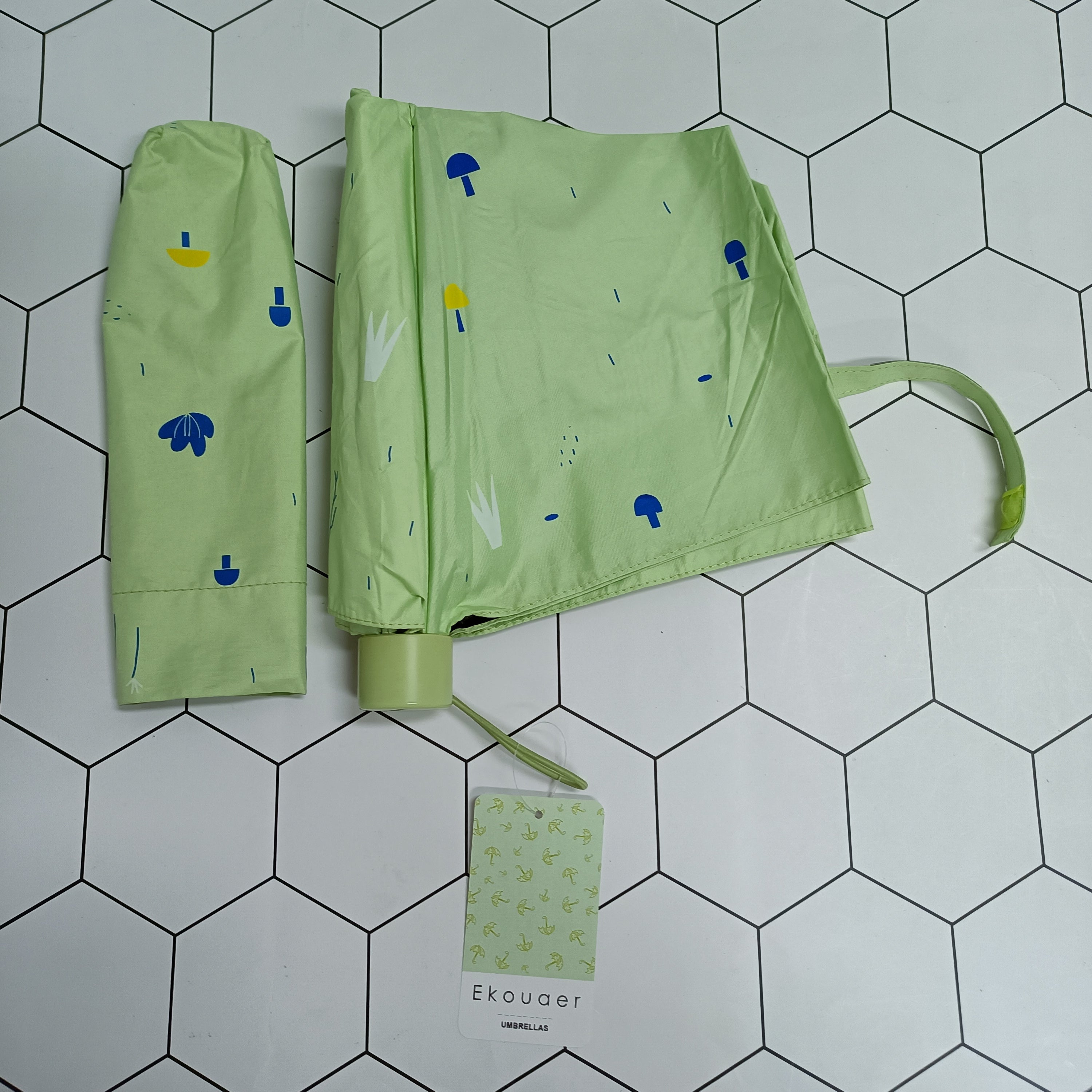 Green umbrella with cartoon print, closed with wrist strap and Ekouaer tag