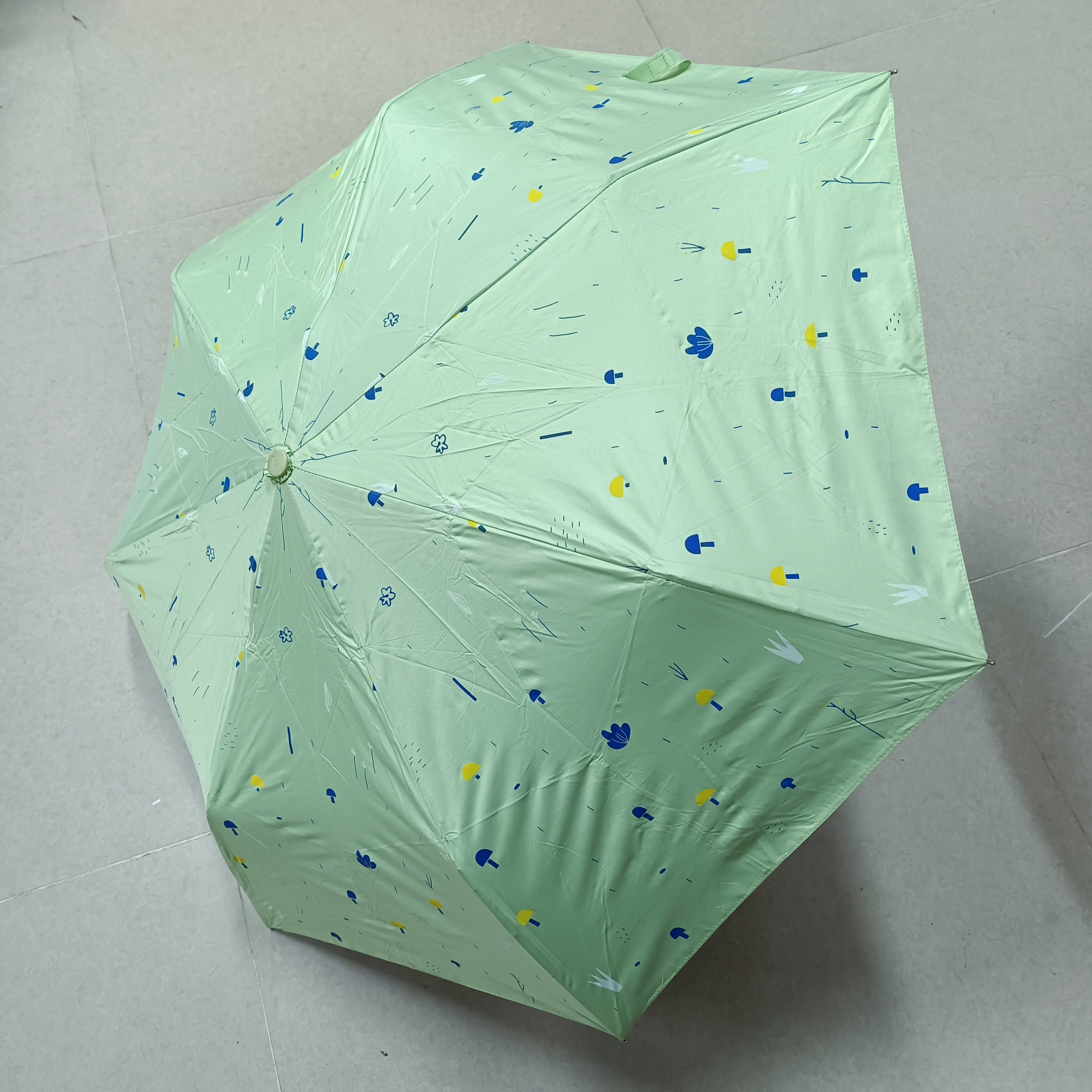 Green canopy umbrella with scattered blue and yellow cartoon icons