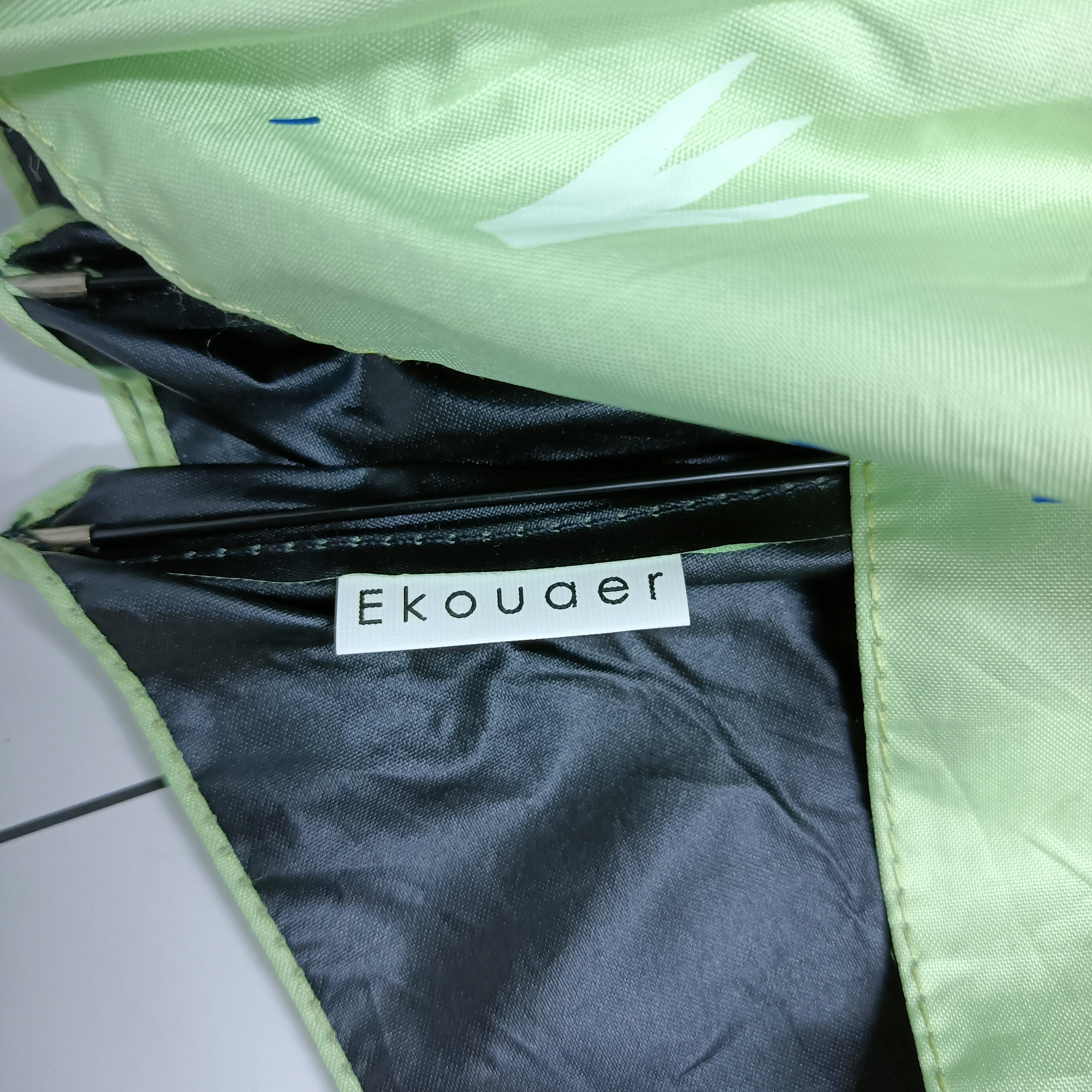 Green umbrella fabric lining with dark label reading Ekouaer