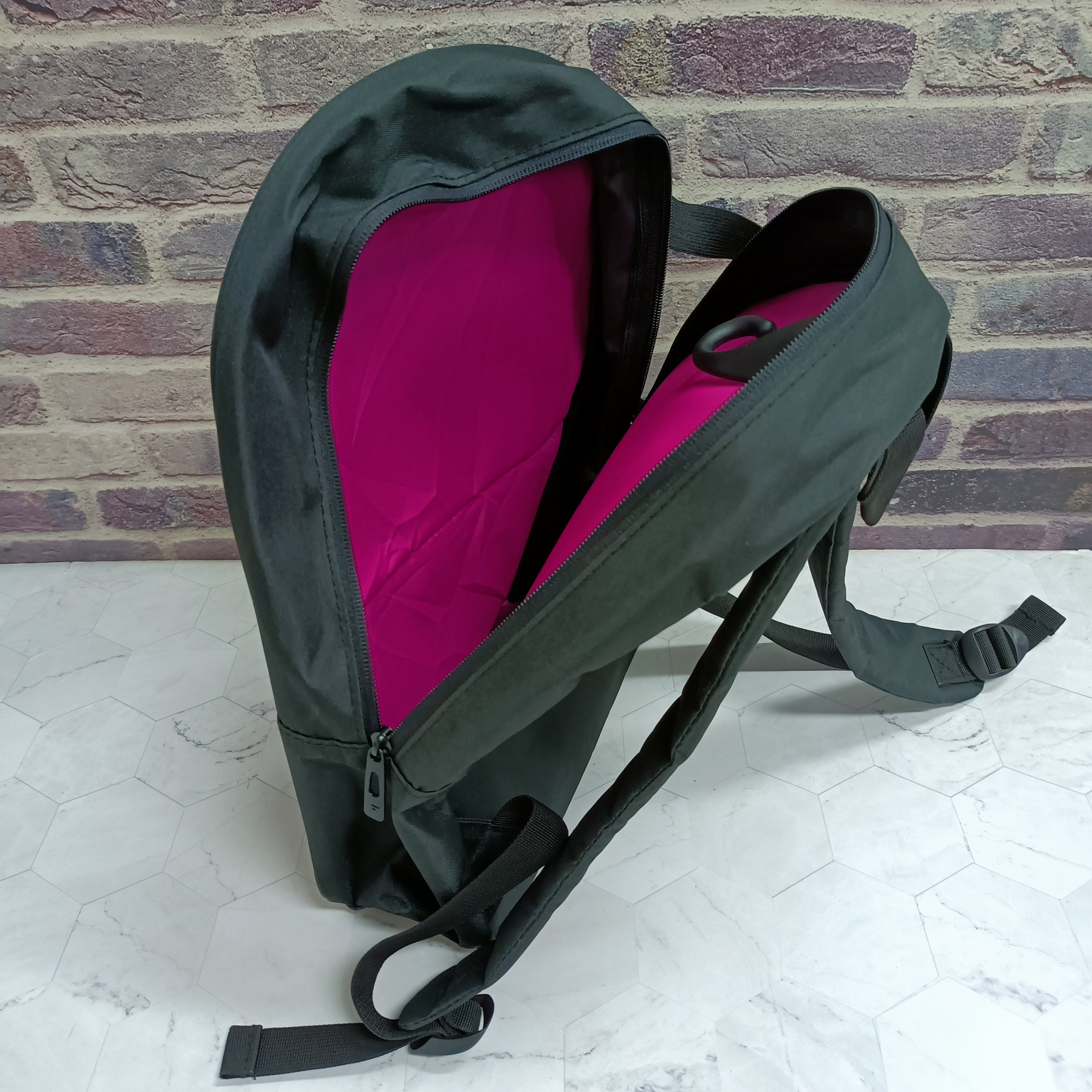 Black backpack open with bright pink interior lining and side straps