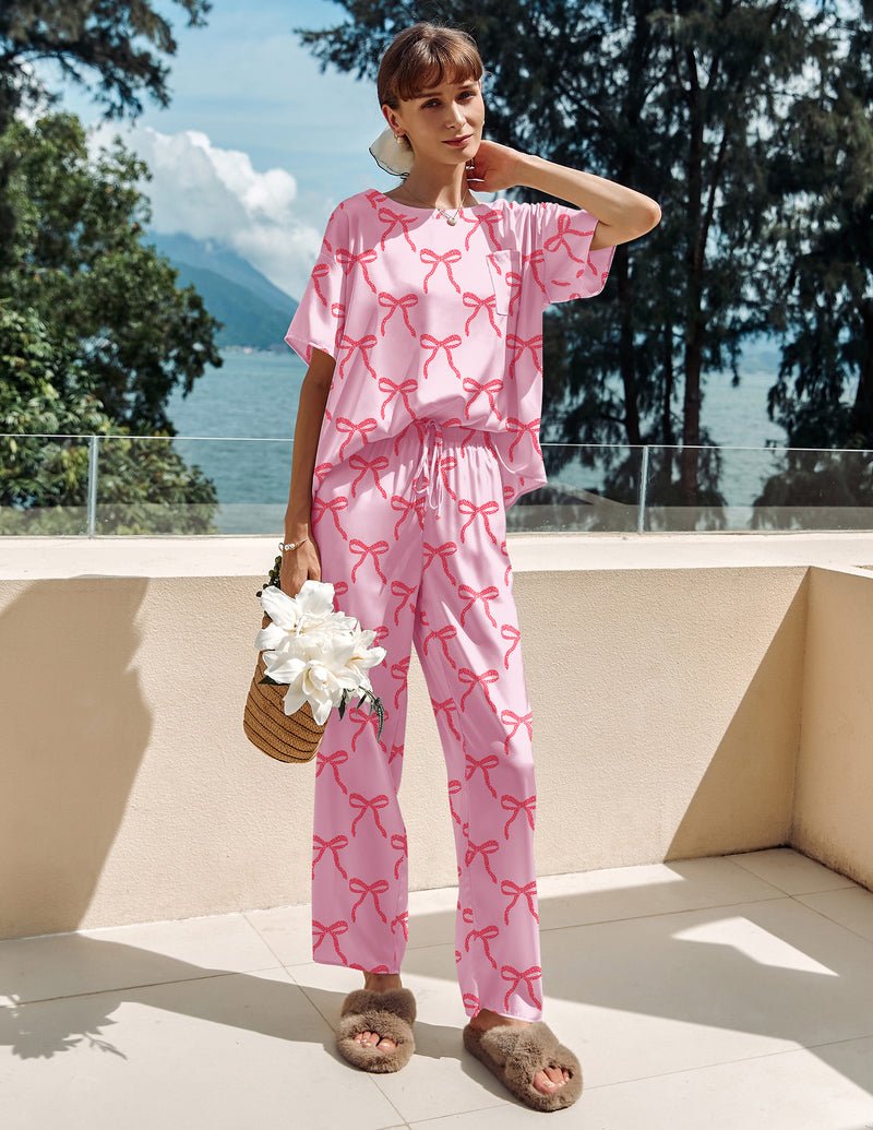 Pink satin pajama set with red bow print, short-sleeve top and matching wide-leg pants