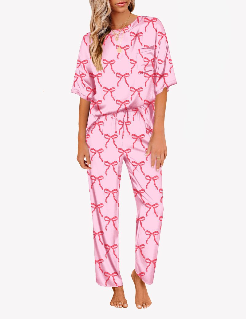 Pink satin pajama set with red bow print, short-sleeve top and long straight pants