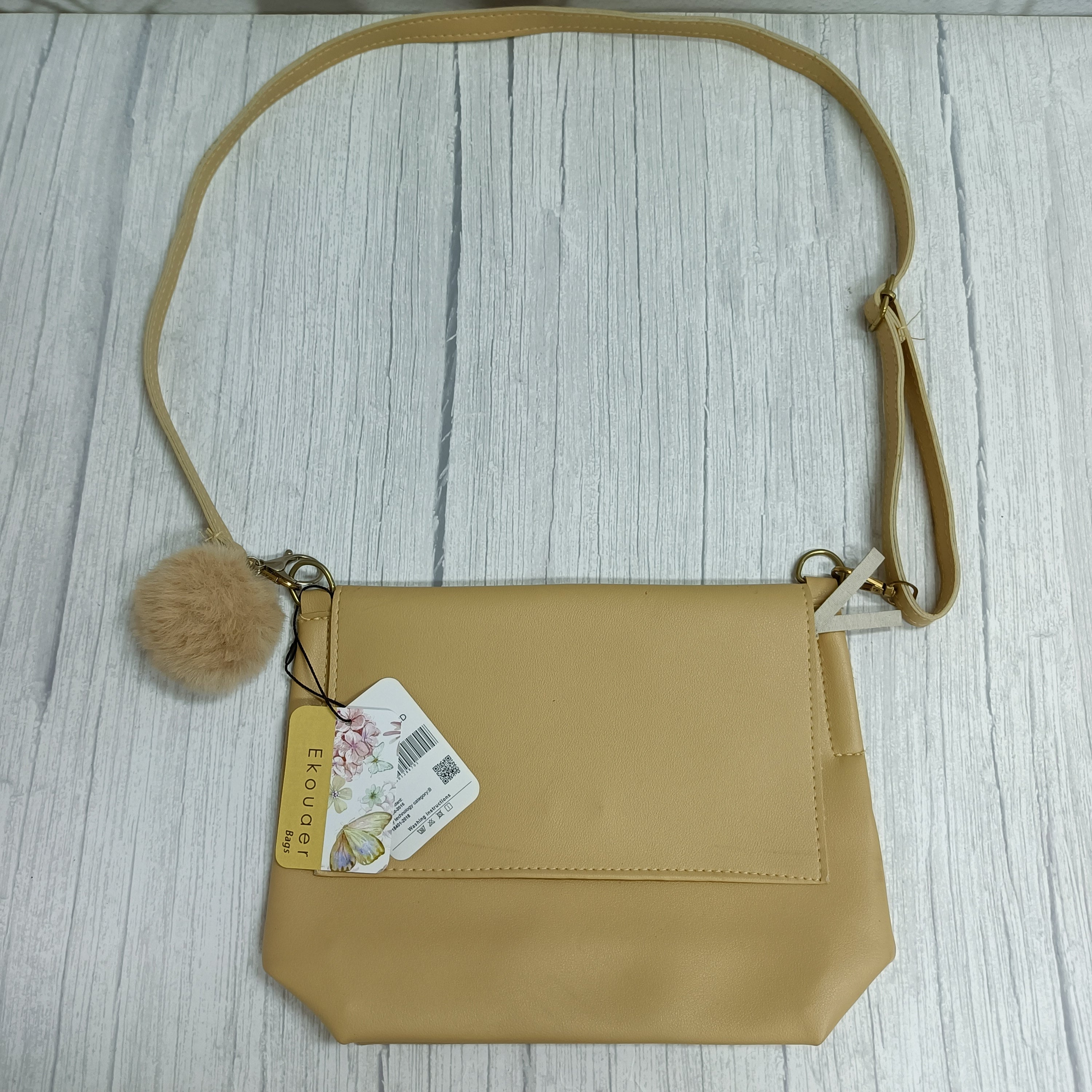 Ekouaer crossbody bag with front flap, pom-pom keychain, and shoulder strap