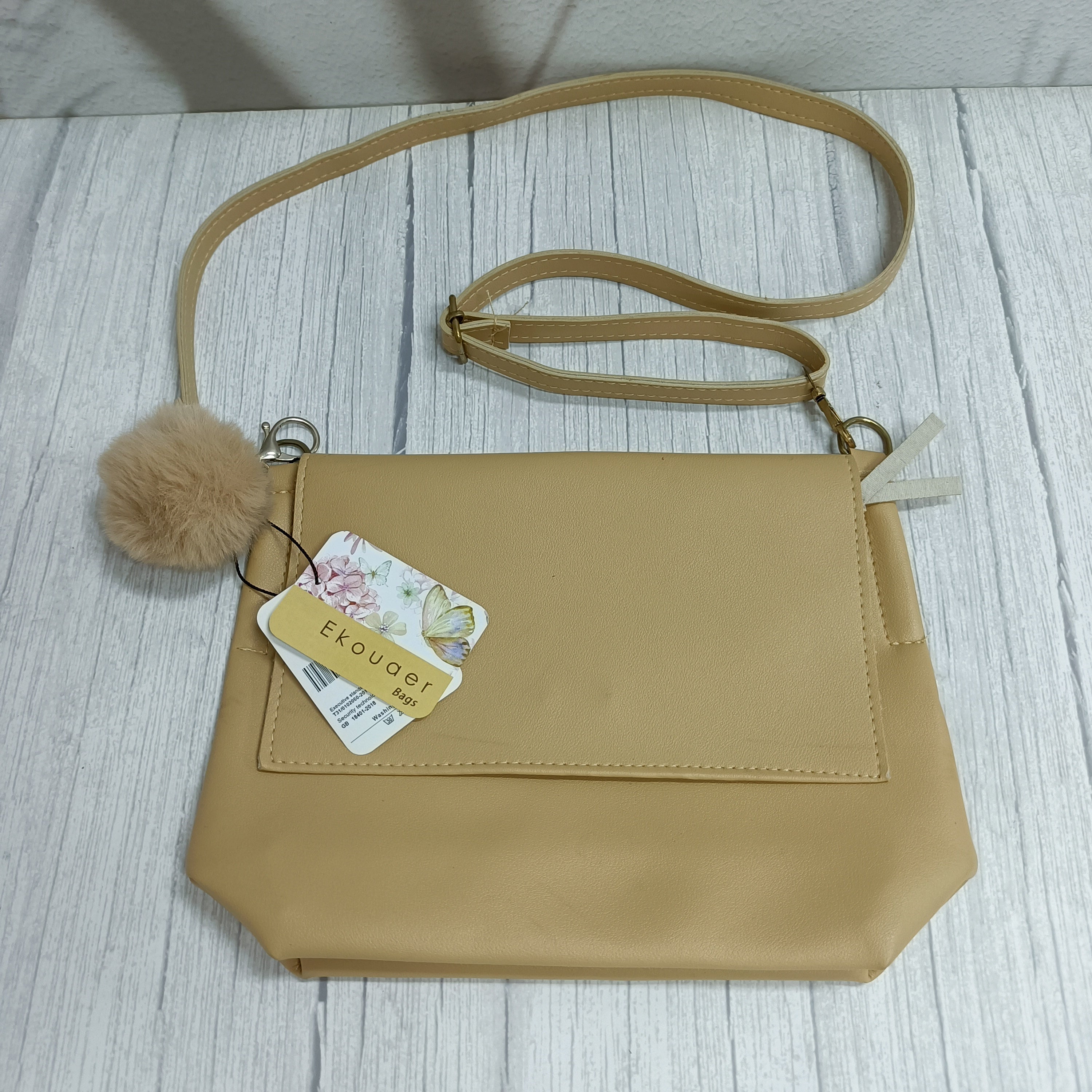 Ekouaer crossbody bag with flap, pom-pom charm, and adjustable shoulder strap