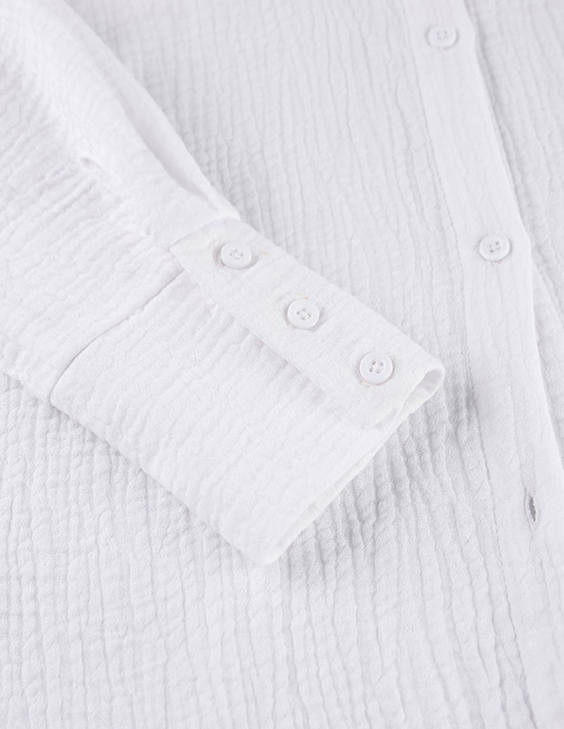 White cotton lounge shirt sleeve cuff and button detail with textured fabric