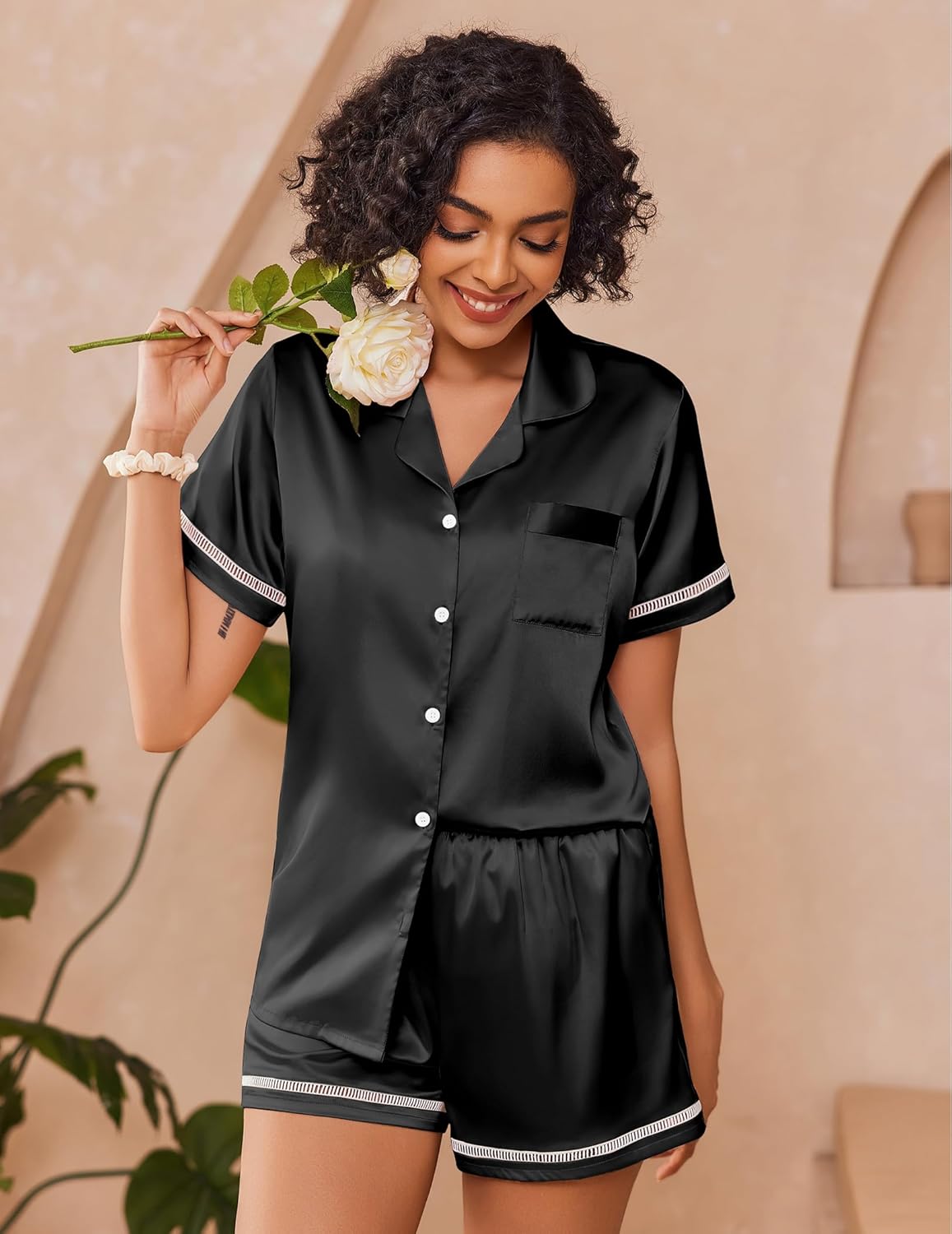 Black satin button-up pajama set with short sleeves, cuff trim, and matching shorts