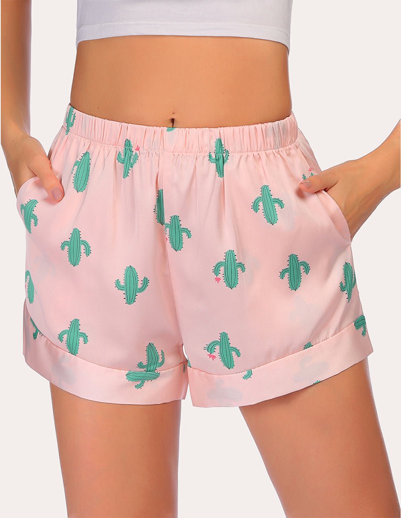 Loose pajama shorts in light pink with green cactus print and elastic waistband, draped fit.