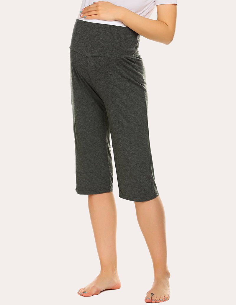 Maternity capri pants in dark green, side-to-front view with elastic waist