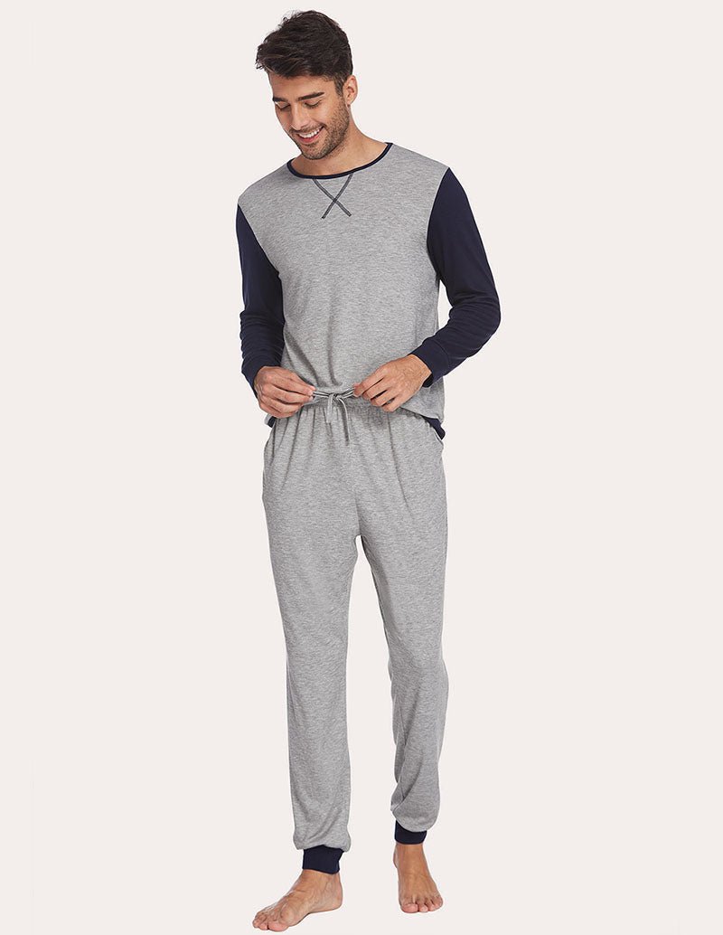 Men's two-piece pajama set with light grey top and navy sleeves; hands at waist drawstring