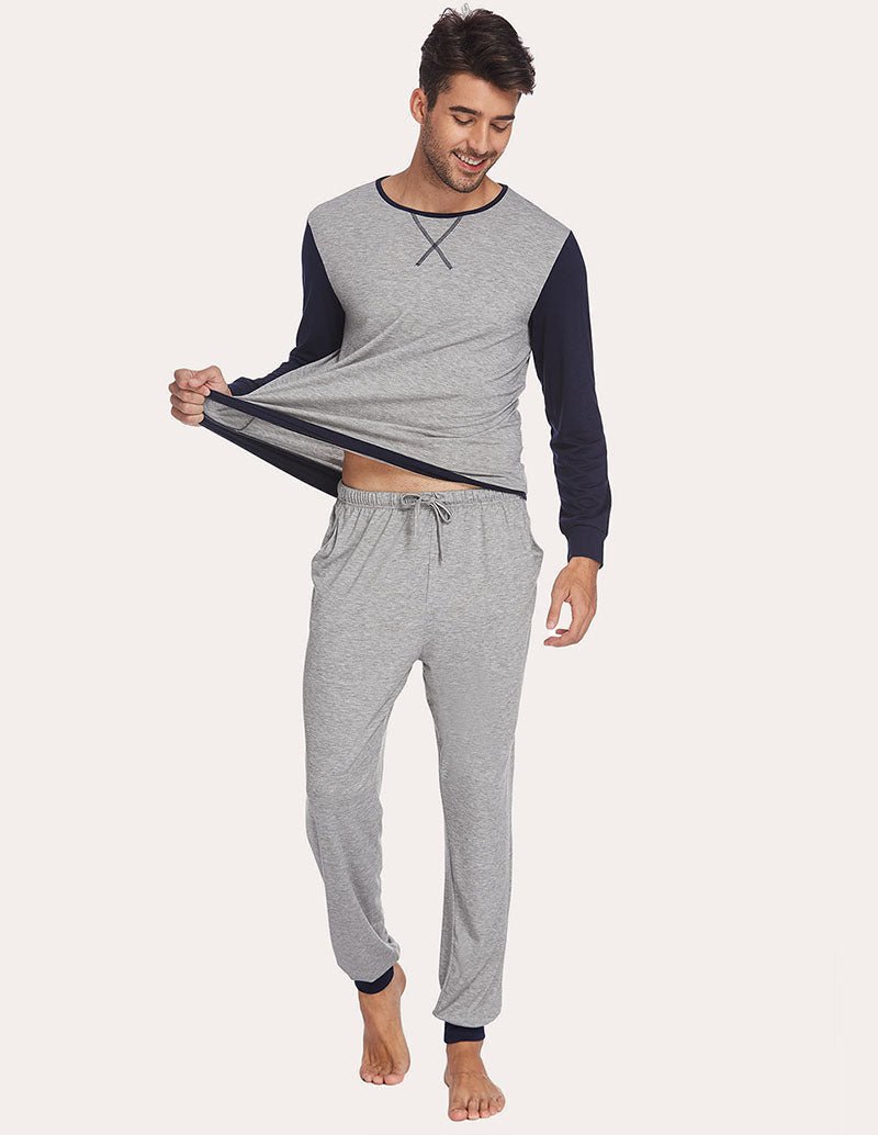 Men's two-piece pajama set with light grey top and jogger pants; holding shirt front