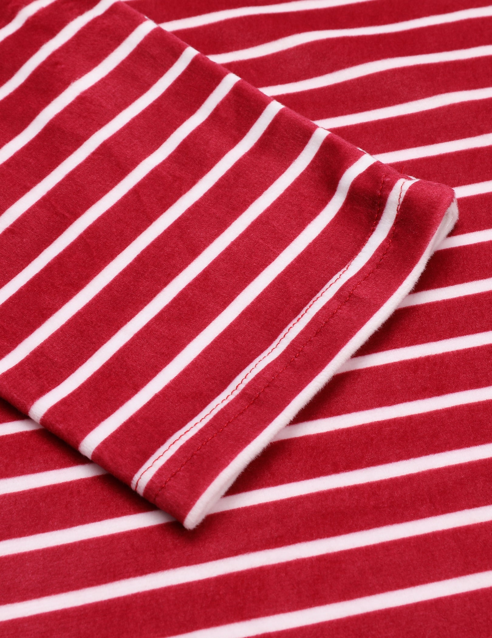 Red velour pajama sleeve cuff with white pinstripes, fabric fold close-up