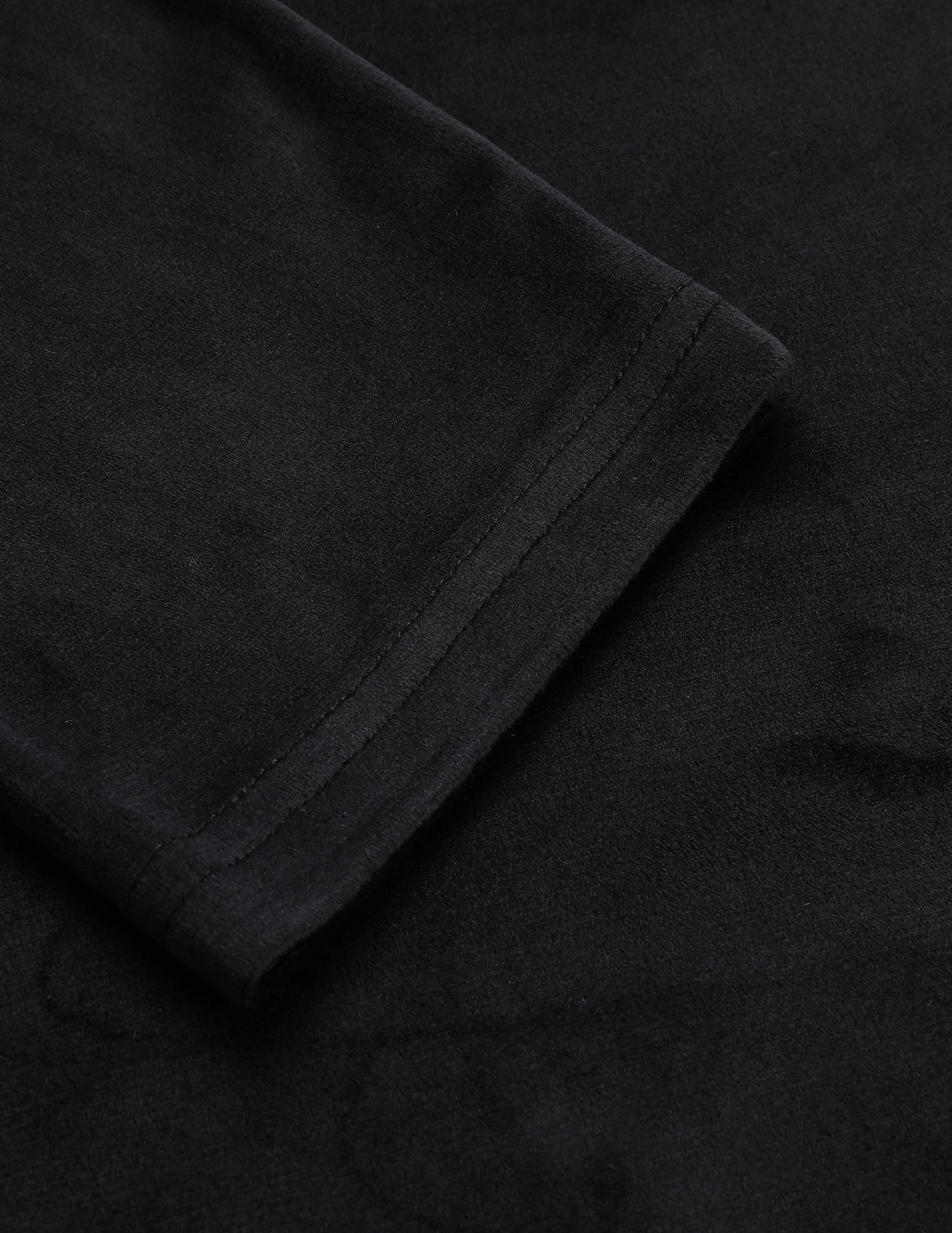 Black velour pajama fabric close-up, folded cuff and seam detail