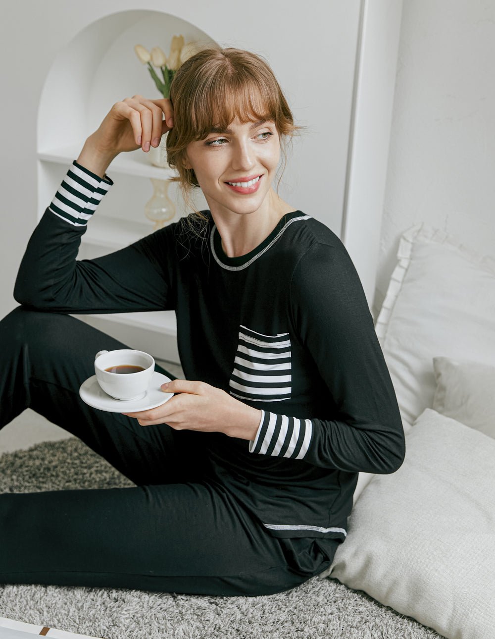 Black pajama set with striped cuffs, crew neckline, and pants worn with slippers